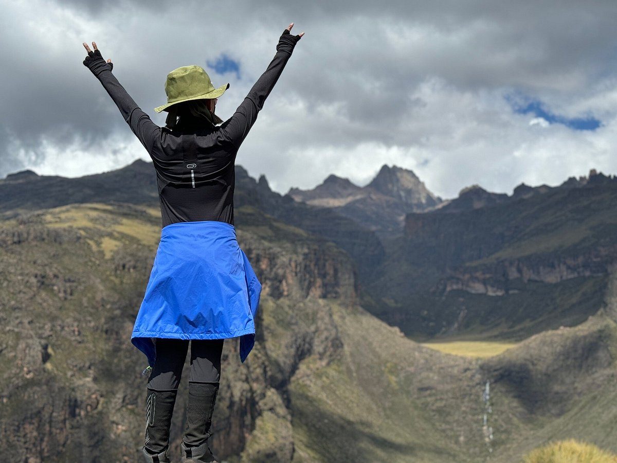 Female hiker with her hands up after seeing Mount Kenya peaks beyond the Gorges valley