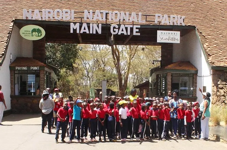A group of primary school students school trip standing in front of Nairobi National Park main gate