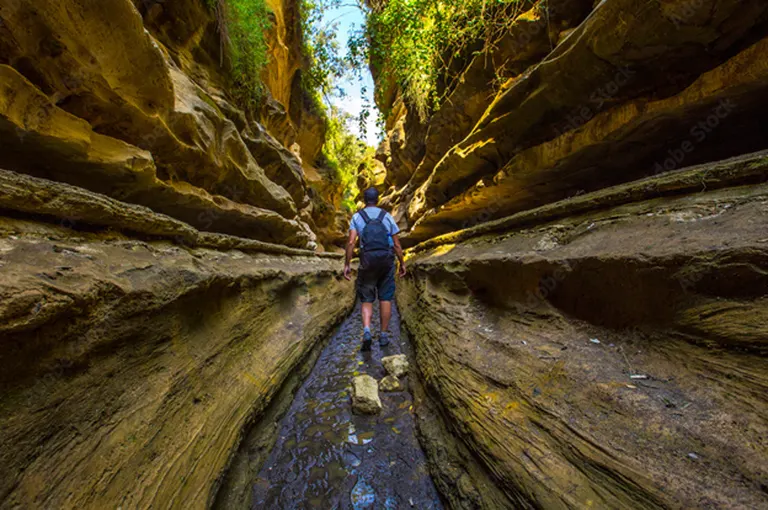 Tourists walking through a deep narrow path of the Hell’s Gate National Park gorges in Kenya