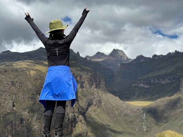 Female hiker with her hands up after seeing Mount Kenya peaks beyond the Gorges valley