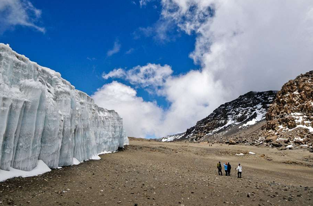 Hikers on Mount Kilimanjaro trek looking at a glacier on the summit of Kilimanjaro, Uhuru Peak Snow.