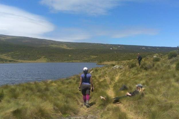 female hikers relaxing on the grass by the shore of Lake Ellis on Mount Kenya. Bright sunny day