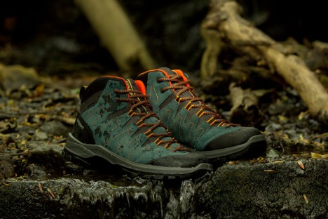 A pair of dark blue, and grey hiking boots with orange shoelaces that are waterproof for trekking