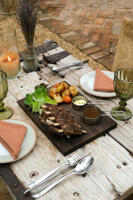 Grilled meat, salad, and sauces on a table with cutlery and glass cups enjoyed on safari in Kenya