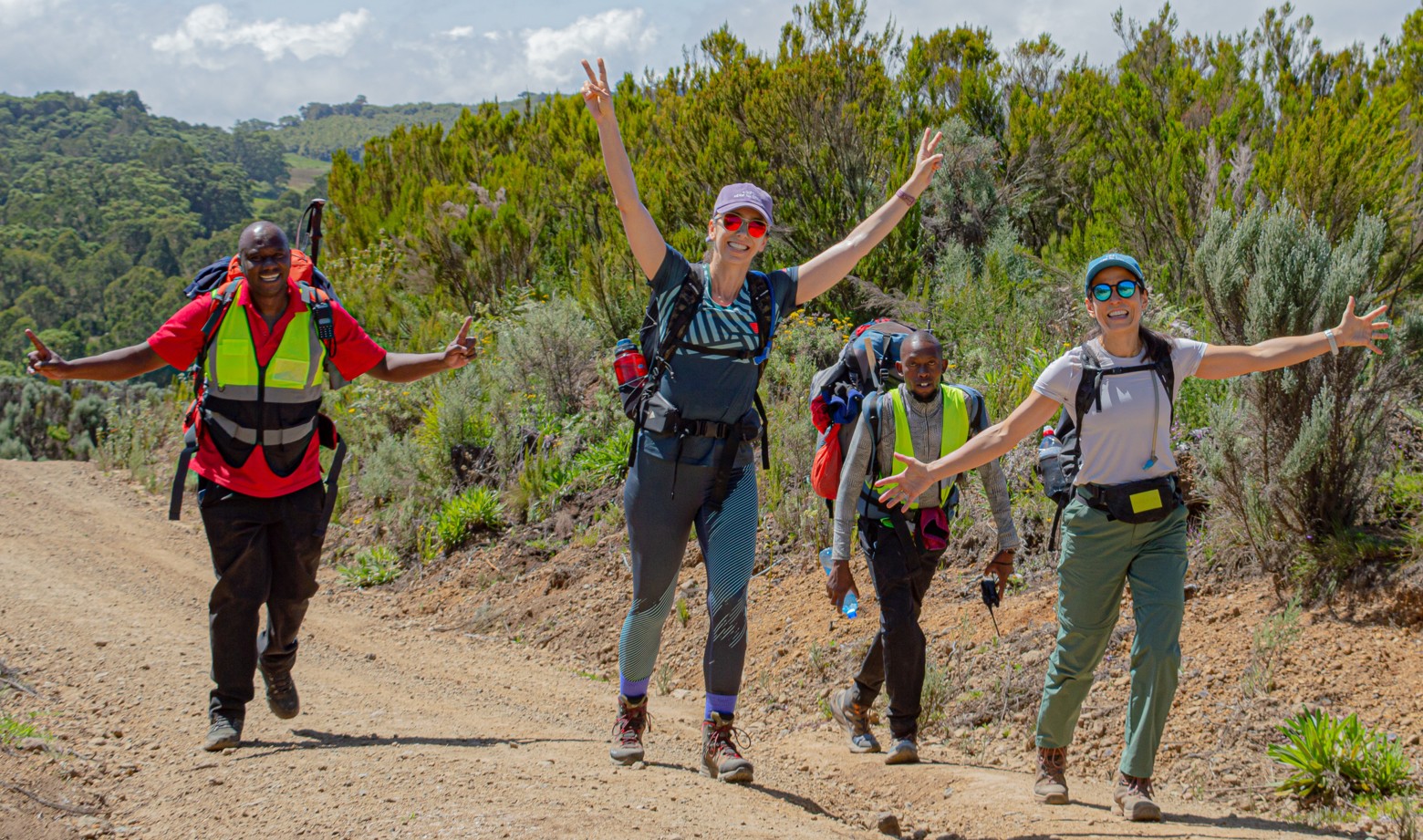 Mount Kenya guides and hikers raising hands and celebrating on the way to the summit