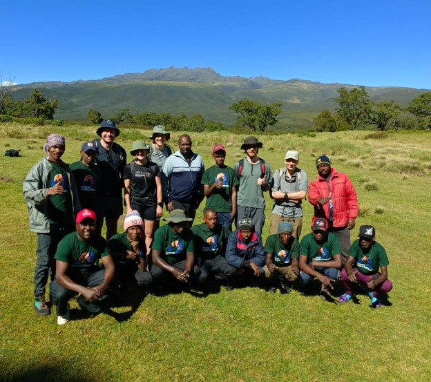 MtKenyaTrekking Expeditions staff wearing branded shirts posing with guests before a safari in Kenya