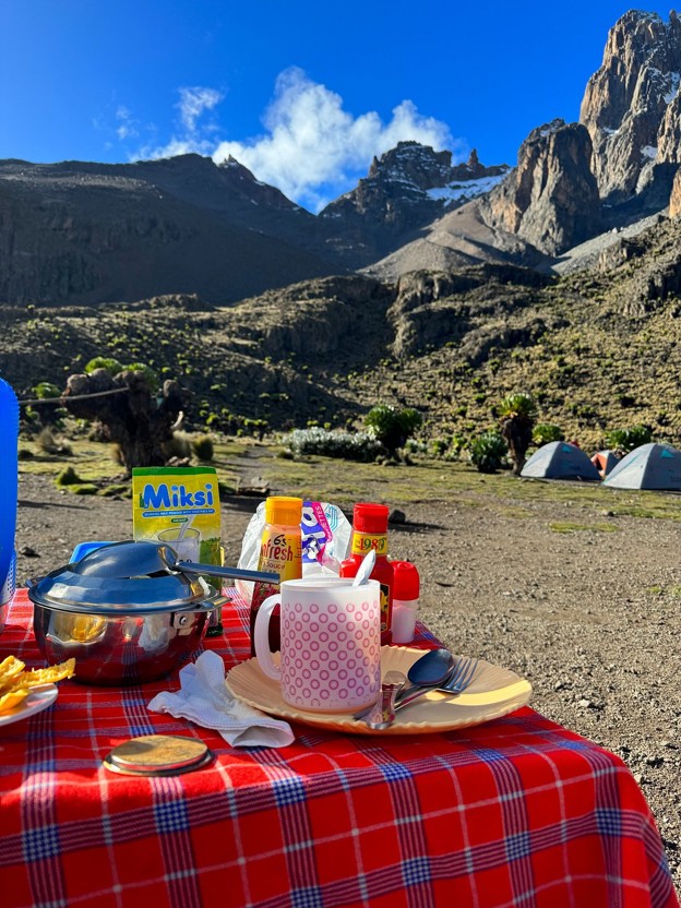 A table with food set up at Shipton’s camp on Mt Kenya. Camp tents below Nelion and Batian peaks
